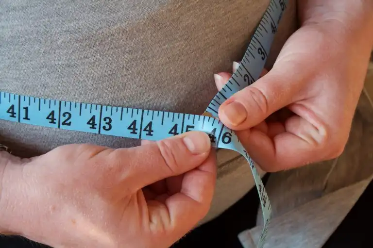 Tape measure around pregnant woman's waist