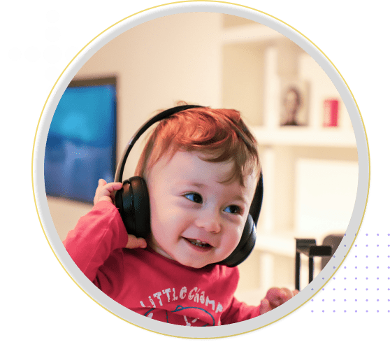 Toddler with large headphones is smiling indoors, benefiting from Applied Behavior Analysis for developmental disabilities and autism